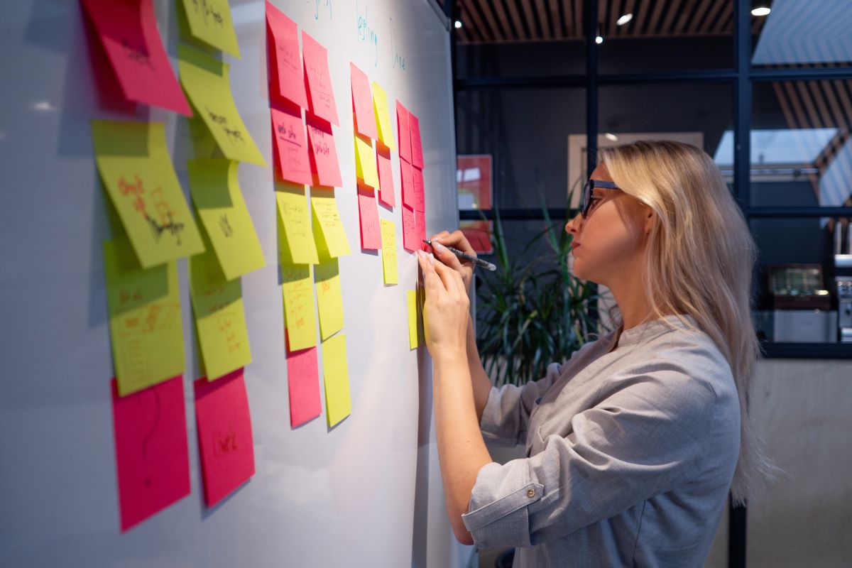 ホワイトボード（whiteboard）に色分けされた付箋を貼ることでTodo管理、スケジュール管理をしている女性